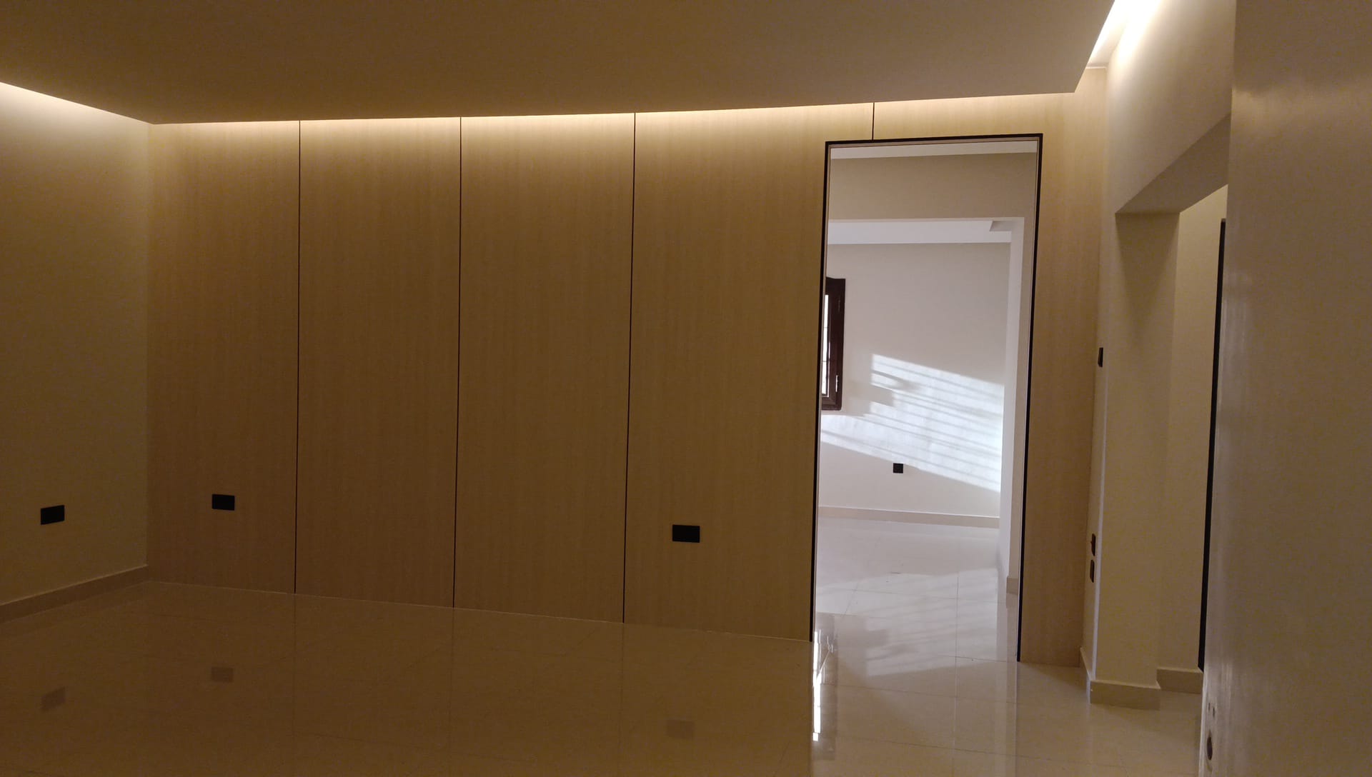 Full-height flush oak-veneer cabinetry running wall to wall under a coved gypsum ceiling
